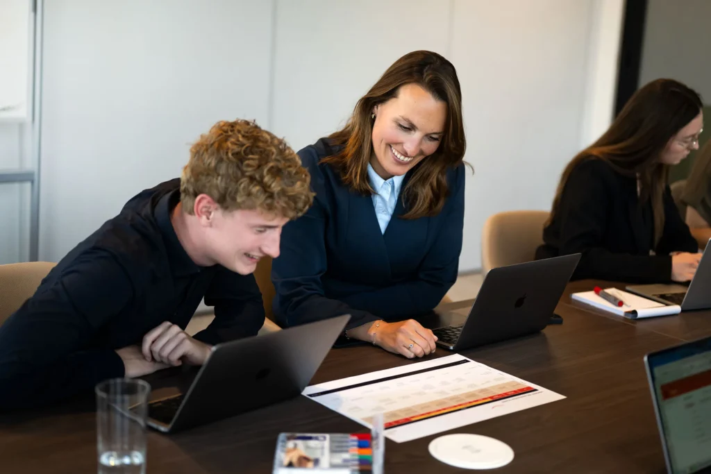 Twee collega's werken samen aan een laptop